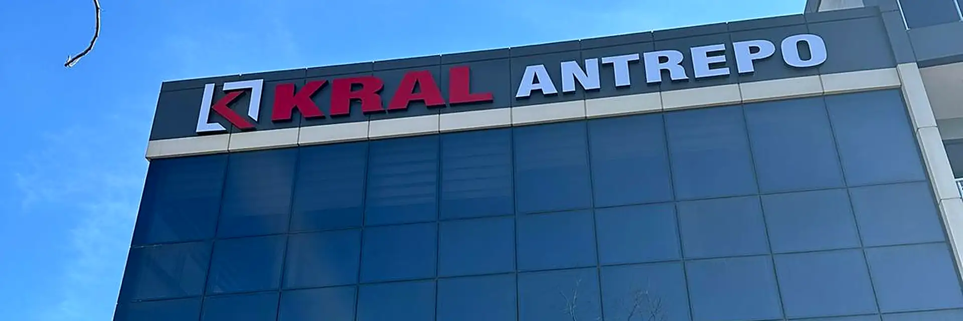 Kral Antrepo idari binası; cam cepheli bina ve çatı tabelası