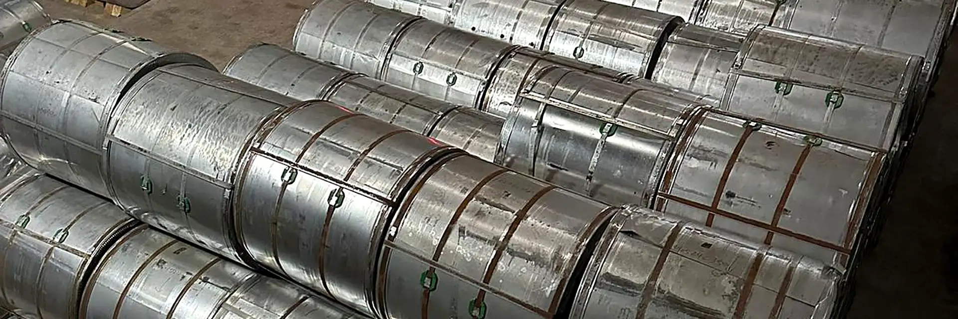 Steel coil stacks in the warehouse with a vehicle loading behind