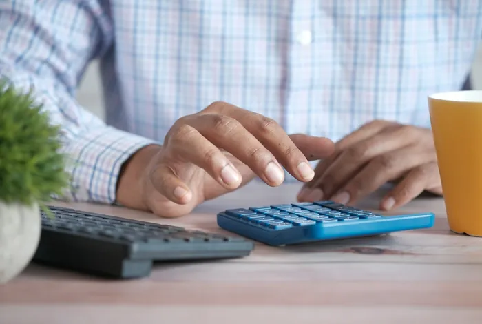Hands working out figures on a calculator at a desk