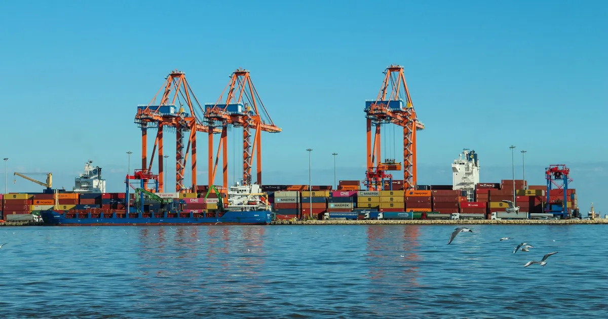 Orange quay cranes and a berthed container ship at a container port